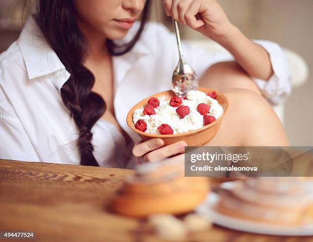 junge frau mit frühstück - hüttenkäse stock-fotos und bilder