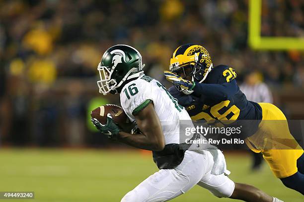 Aaron Burbridge of the Michigan State Spartans makes a catch in the fourth quarter and tackled by Jourdan Lewis of the Michigan Wolverines at...