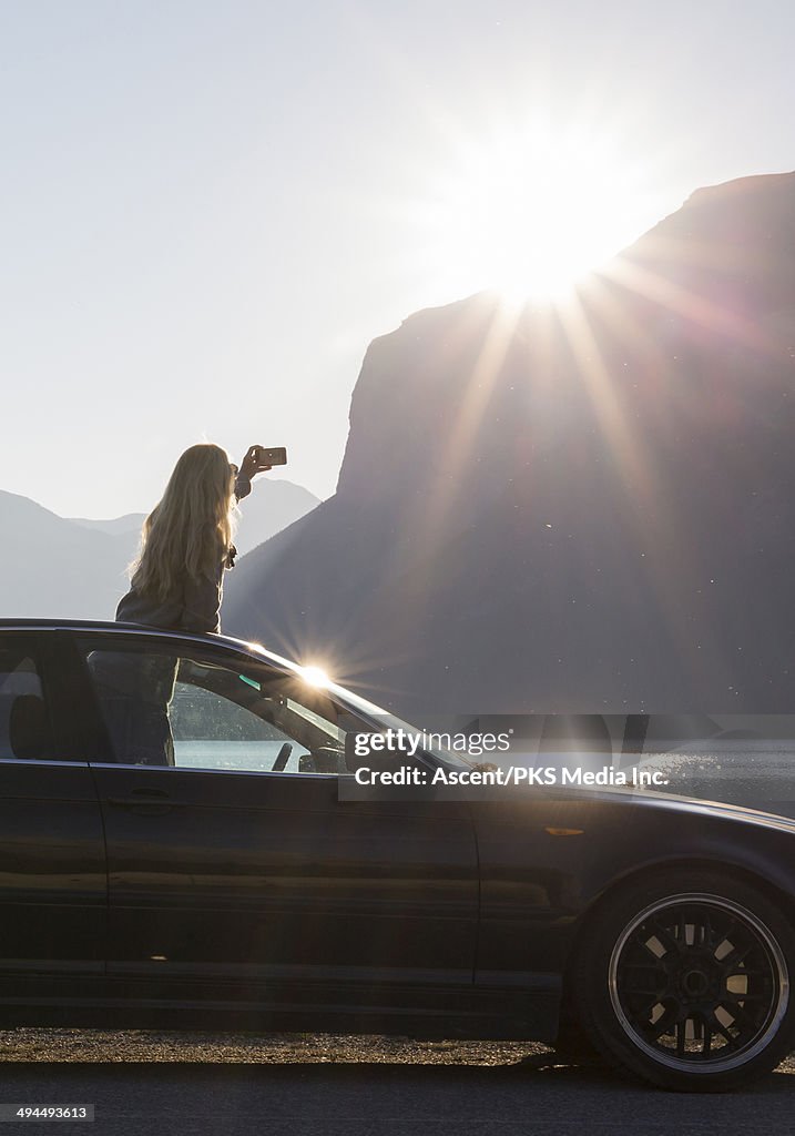 Woman taking smart phone pic from car