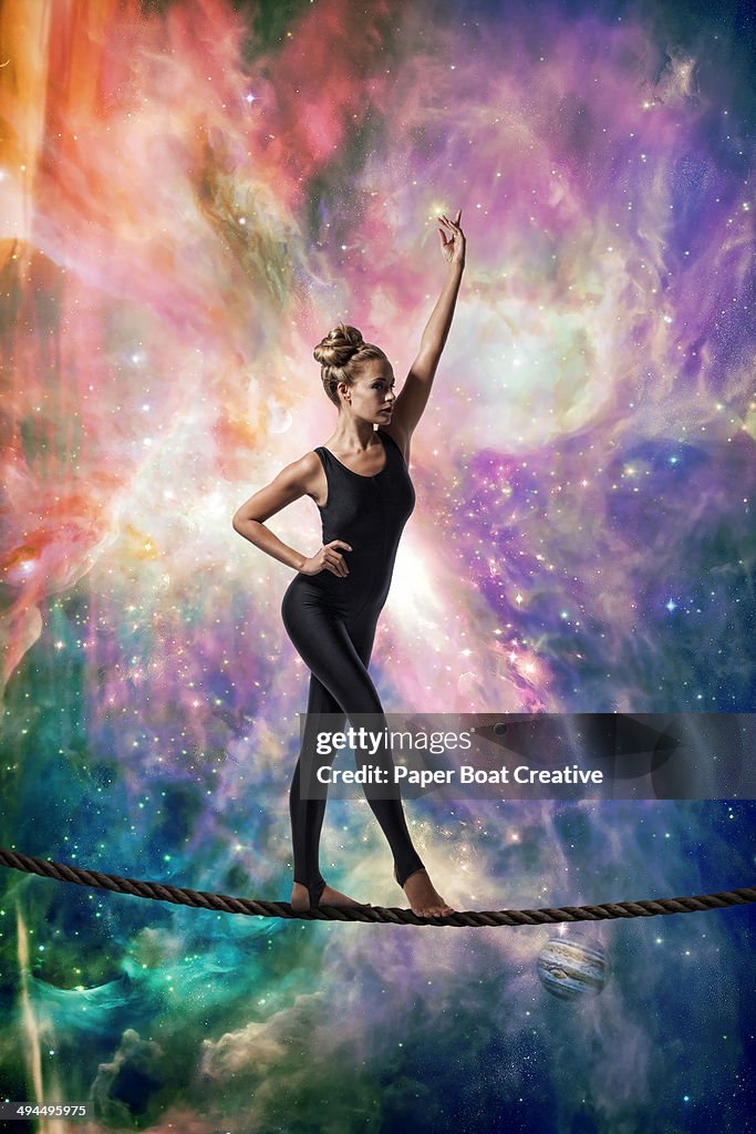 Gymnast balancing on a rope against cosmic sky