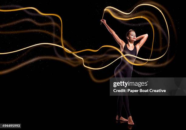 gymnast waving golden sparkly ribbon - long exposure dance stock pictures, royalty-free photos & images