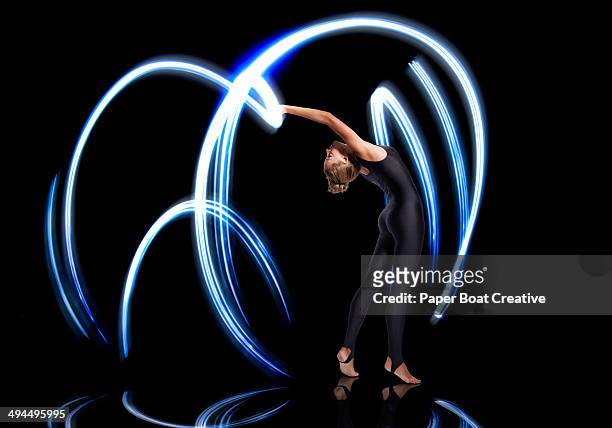 gymnast making electric blue light streaks - long exposure dancer stock-fotos und bilder