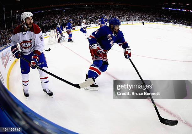 Raphael Diaz of the New York Rangers plays the puck along the boards against Brandon Prust of the Montreal Canadiens during Game Six of the Eastern...