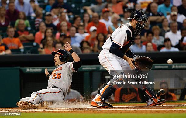 Steve Pearce of the Baltimore Orioles slides safe into home plate in the fourth inning as Jason Castro of the Houston Astros waits for the ball...