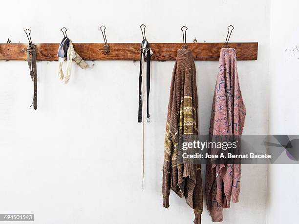 wooden coat rack wall hanging with old clothes - portemanteau photos et images de collection