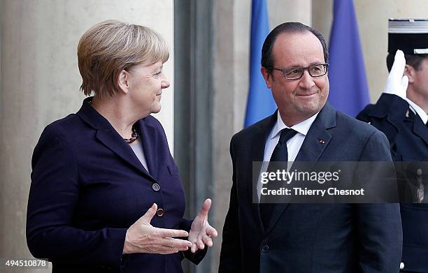 French President Francois Hollande welcomes German Chancellor Angela Merkel prior to a meeting at the Elysee Presidential Palace on October 27, 2015...