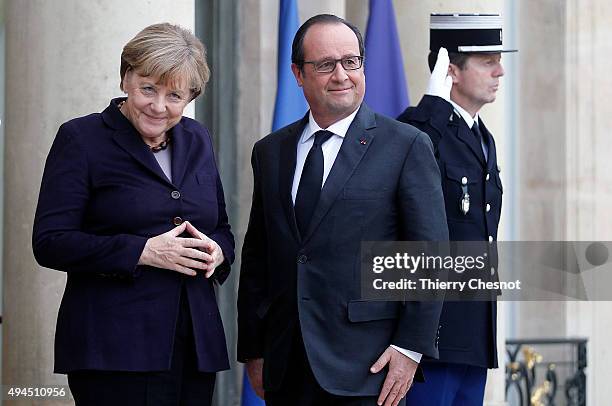 French President Francois Hollande welcomes German Chancellor Angela Merkel prior to a meeting at the Elysee Presidential Palace on October 27, 2015...