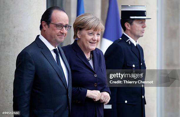 French President Francois Hollande welcomes German Chancellor Angela Merkel prior to a meeting at the Elysee Presidential Palace on October 27, 2015...