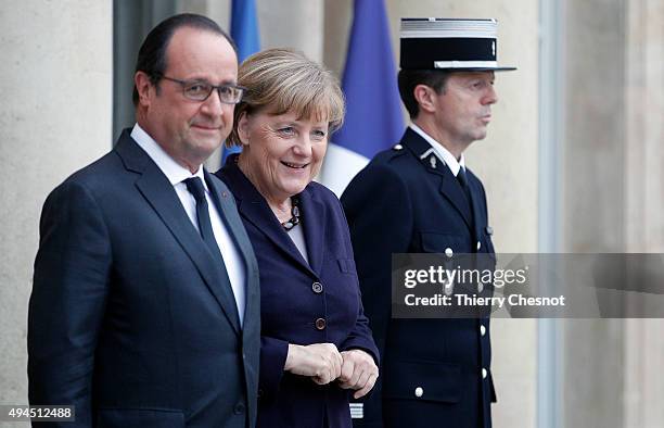 French President Francois Hollande welcomes German Chancellor Angela Merkel prior to a meeting at the Elysee Presidential Palace on October 27, 2015...