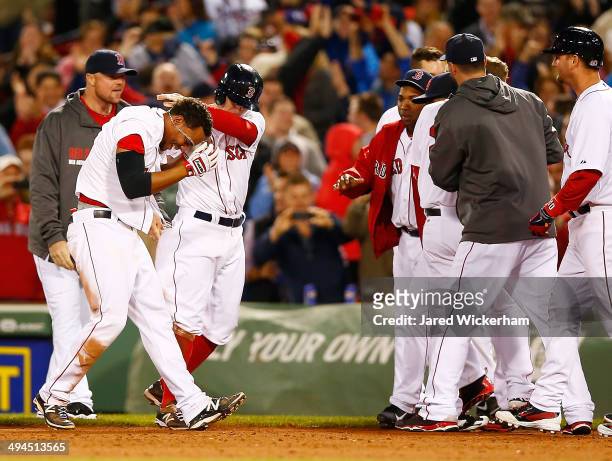 Xander Bogaerts of the Boston Red Sox is mobbed by his teammates including Brock Holt after hitting the walk-off game-winning RBI single in the 9th...