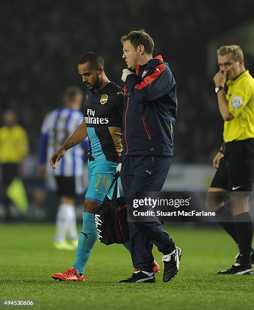 Injured Arsenal striker Theo Walcott leaves the pitch with physio Colin Lewin during the Capital One Cup Fourth Round match between Sheffield...