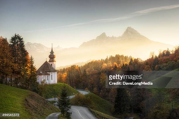 bavarian alps with sunset shining on remote church - beieren stockfoto's en -beelden