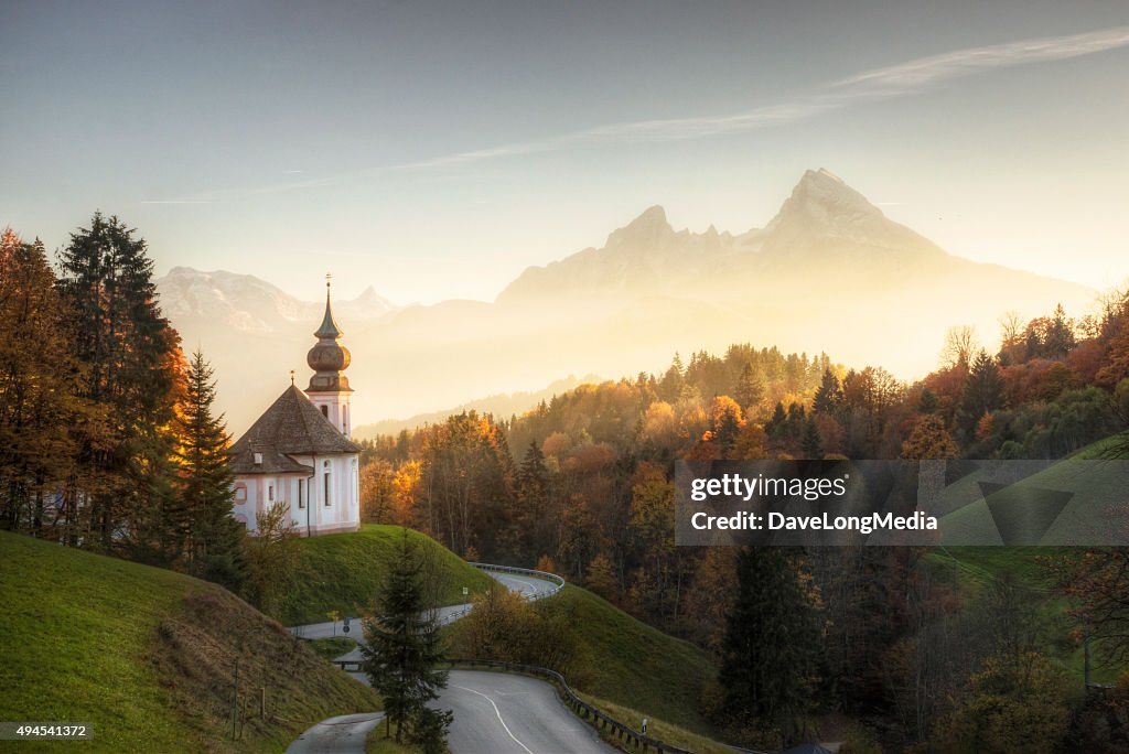 Alpes Bávaros com pôr do sol brilhando sobre Igreja remoto