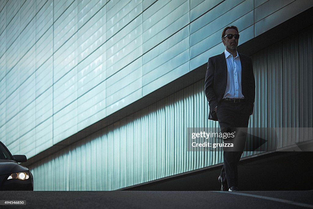 Handsome classy man in suit walks down the city street