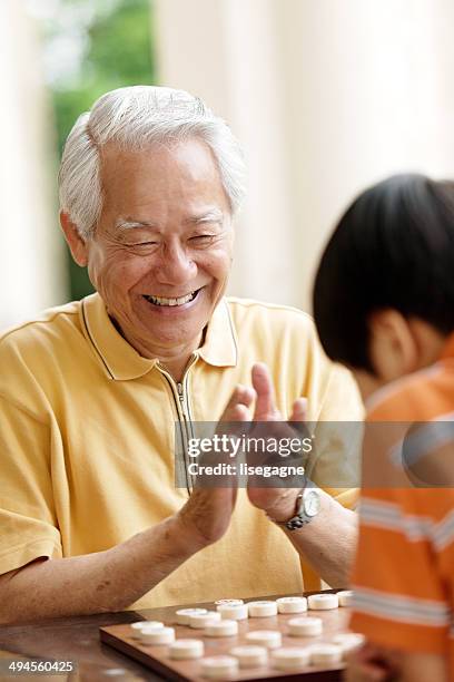 grandfather and grandson playing xiangqi (chinese chess) - clapping hands stock pictures, royalty-free photos & images