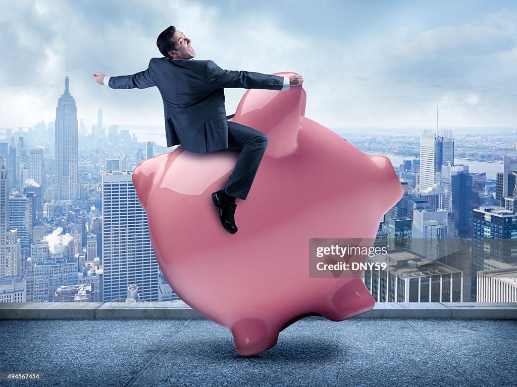 Businessman Riding A Piggy Bank In Urban Scene