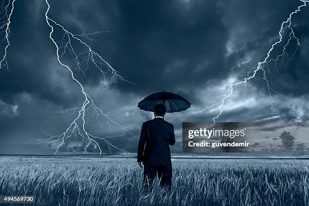 man in black suit with a black umbrella in a storm - lightning protection stock pictures, royalty-free photos & images