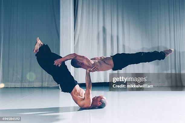 strong teamwork with two acrobats supporting each other - acrobatiek stockfoto's en -beelden