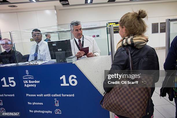 Border Force check the passports of passengers arriving at Gatwick Airport on May 28, 2014 in London, England. Border Force is the law enforcement...