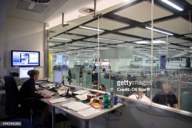 Border Force staff monitor the checking of passports of passengers arriving at Gatwick Airport from their control room on May 28, 2014 in London,...