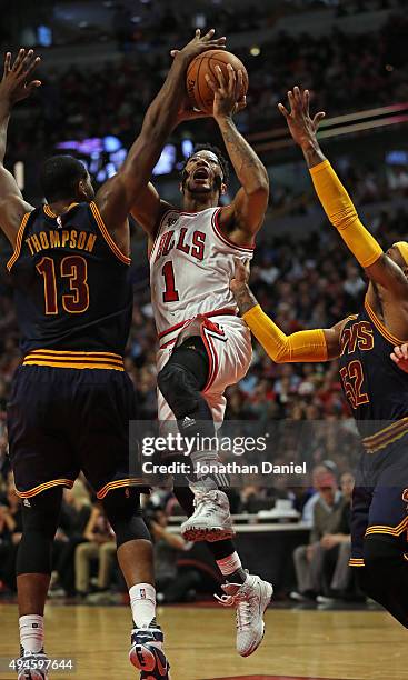 Derrick Rose of the Chicago Bulls is fouled as he tries to drive between Tristan Thompson and Mo Williams of the Cleveland Cavaliers during the...