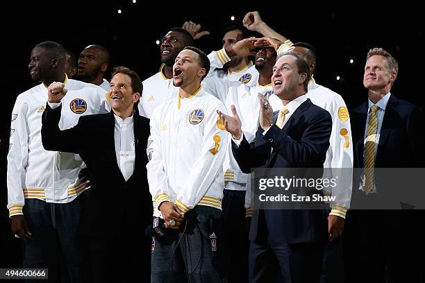 Stephen Curry of the Golden State Warriors celebrates with owners Peter Guber and Joe Lacob as their 2015 championship banner is unveiled prior to...