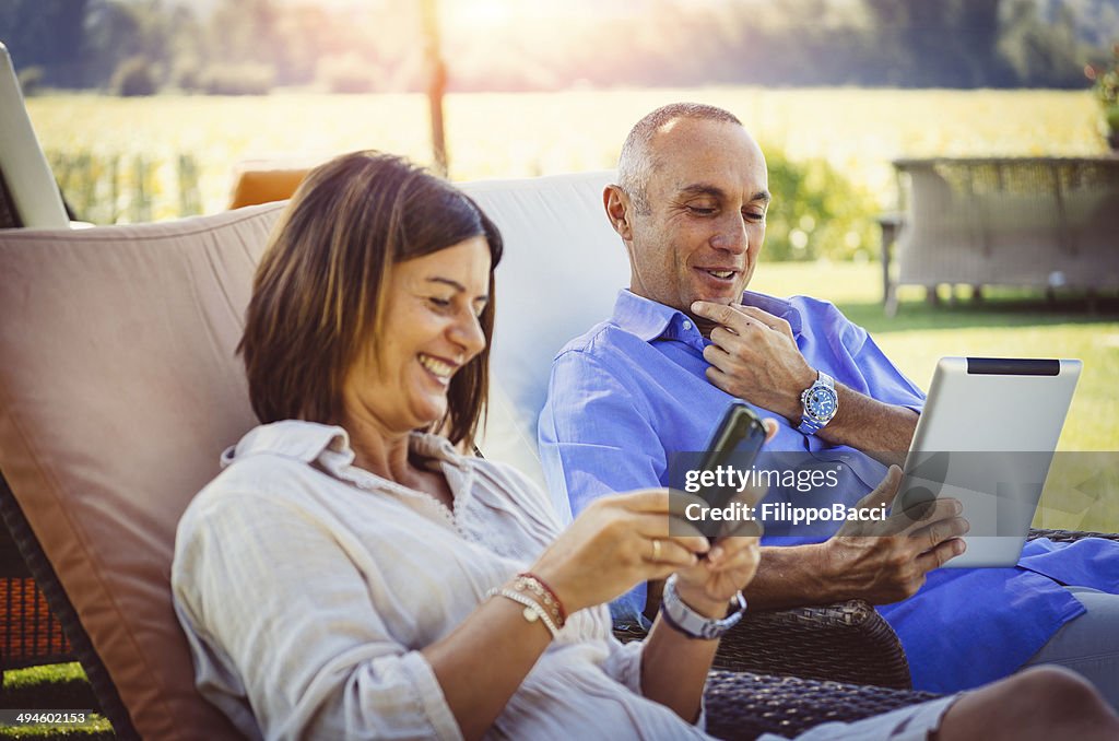 Adult couple relaxing with digital tablet at resort