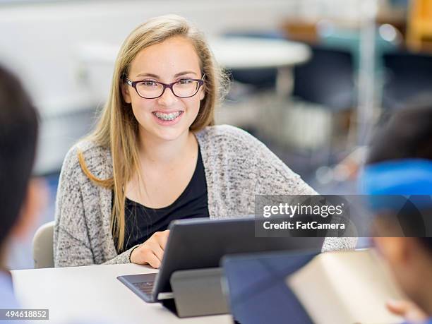 teenage girl happily writing a paper on a laptop - teenage girl blonde hair and braces stock pictures, royalty-free photos & images