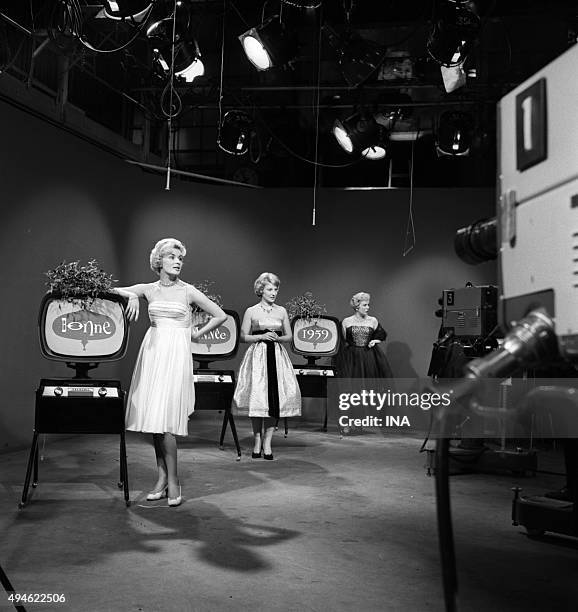 In studio, in front of cameras, the announcers Jacqueline Huet, Jacqueline Caurat, and Catherine Langeais, in evening dress next to television sets...