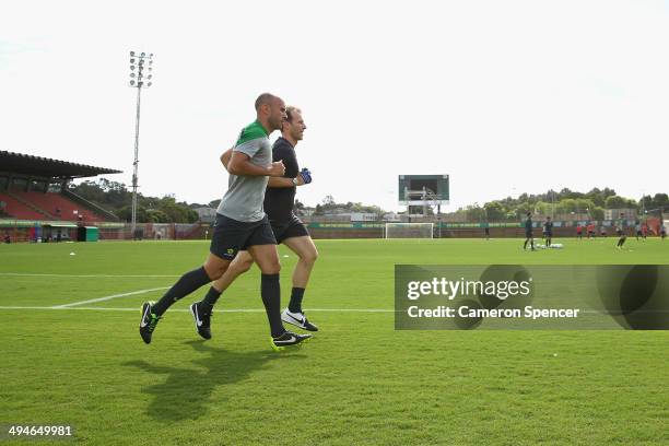 Mark Bresciano of the Socceroos runs with a trainer during an Australian Socceroos training session at Arena Unimed Sicoob on May 30, 2014 in...