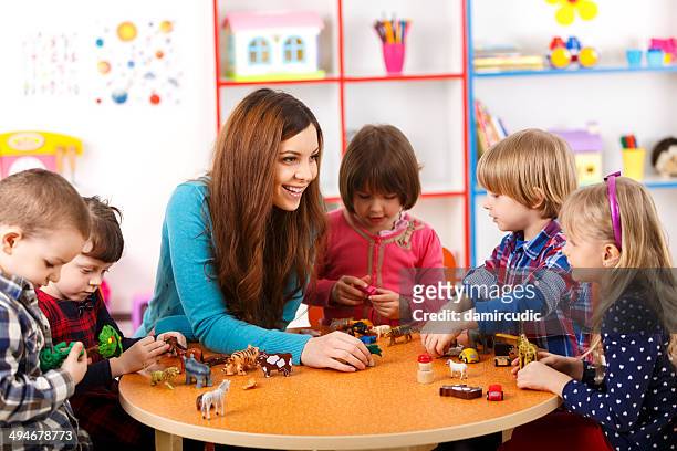 young woman playing with kids in nursery school - horses playing stock pictures, royalty-free photos & images