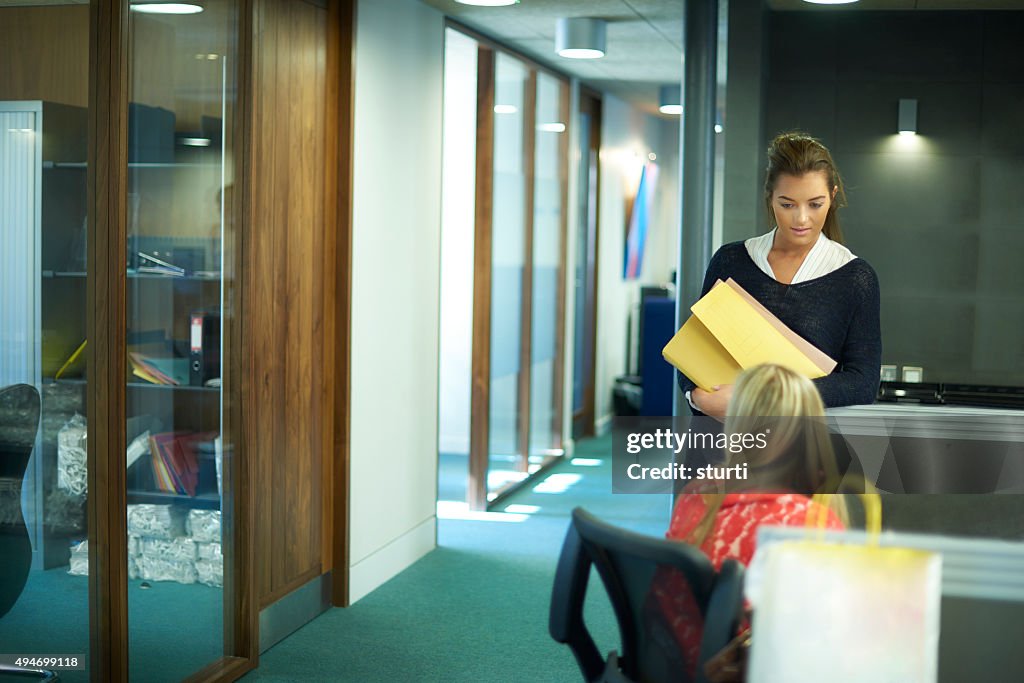 Two young female office workers chatting