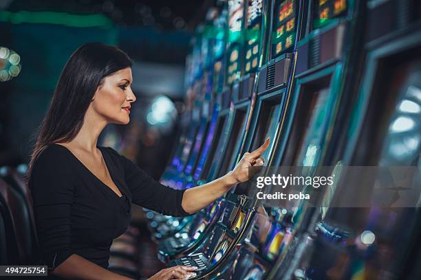 woman playing slot machine in casino - fruit machine stock pictures, royalty-free photos & images