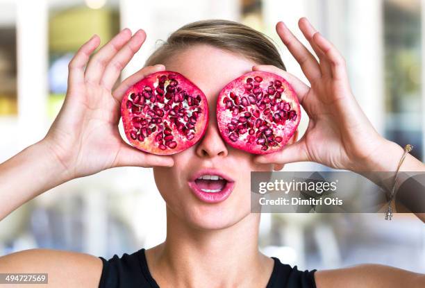 young woman holding pomegranate slices as glasses - antioxidant stockfoto's en -beelden