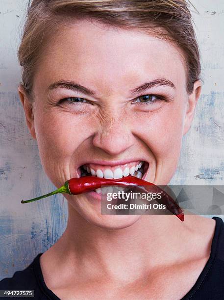 young woman biting red hot chilli - peppar bildbanksfoton och bilder