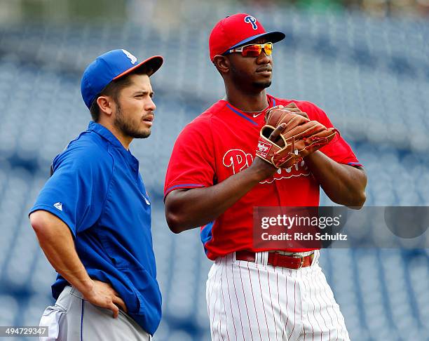 Travis d'Arnaud of the New York Mets talks with Domonic Brown of the Philadelphia Phillies before the start of their game at Citizens Bank Park on...