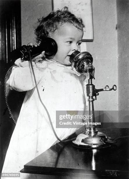 Toddler using a candlestick telephone, circa 1940.