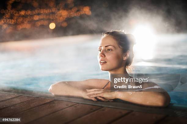 woman spending a winter night in a heated swimming pool. - winter swimming pool stockfoto's en -beelden