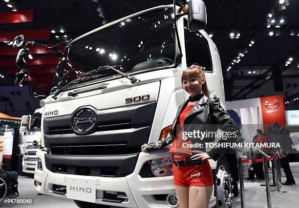 Model stands beside a Hino 500 truck at the Tokyo Motor Show in Tokyo on October 29, 2015. The biennial motor show's 44th edition, which runs until...