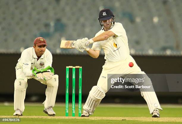 Travis Dean of Victoria bats as wicketkeeper Chris Hartley of Queensland looks on during day two of the Sheffield Shield match between Victoria and...