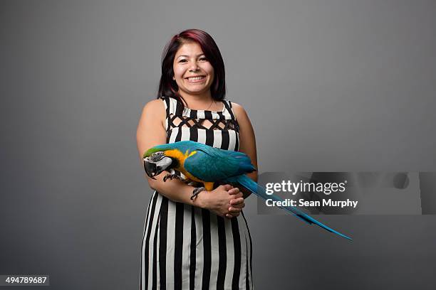 woman in stripes holding blue-and-gold macaw - blue and yellow macaw stock pictures, royalty-free photos & images