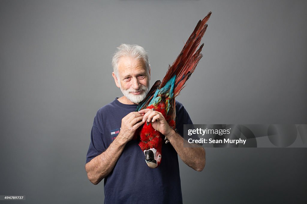 Man holding Red-and-green Macaw upside down