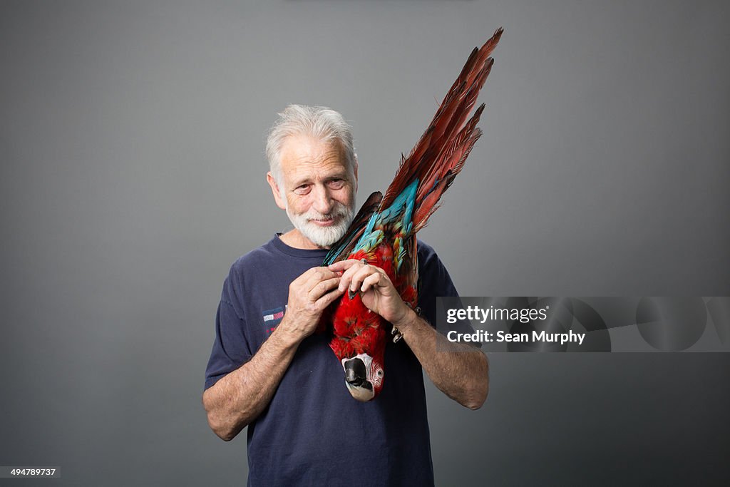 Man holding Red-and-green Macaw upside down