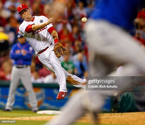 Third baseman Reid Brignac of the Philadelphia Phillies throws to first base but Juan Lagares of the New York Mets beats the throw for a single...