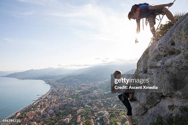 rock climber instructing partner - sun flare couple stockfoto's en -beelden