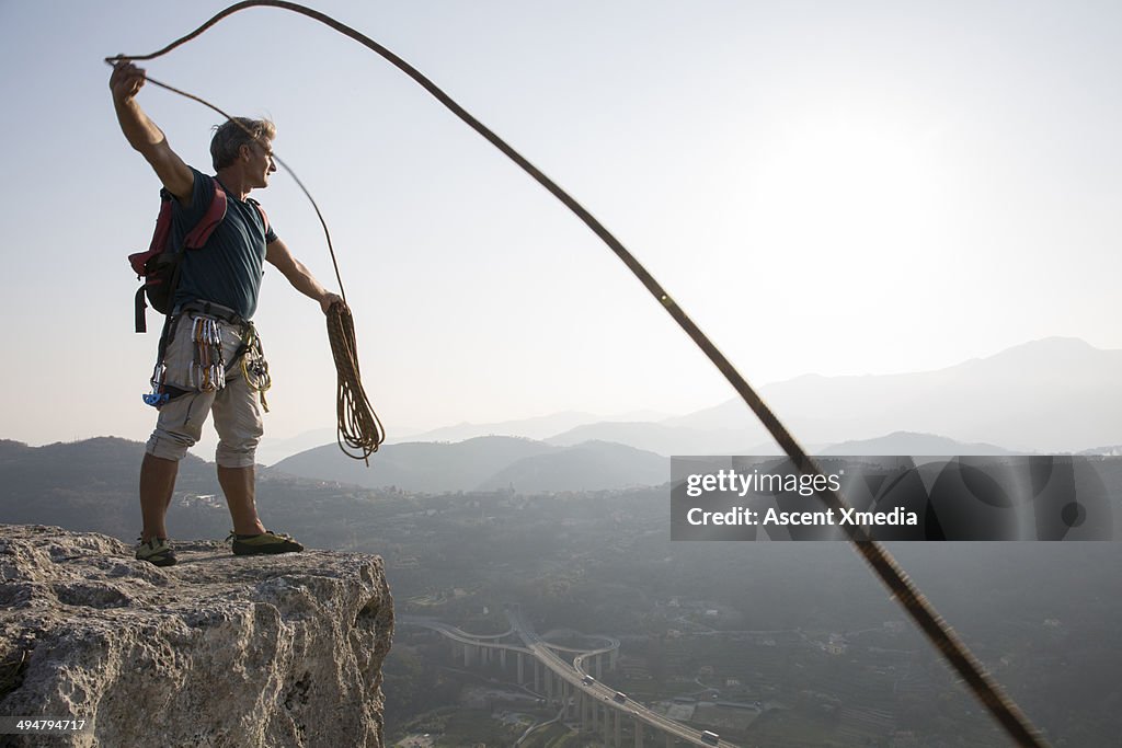 Rock climber coils rope at end of climb
