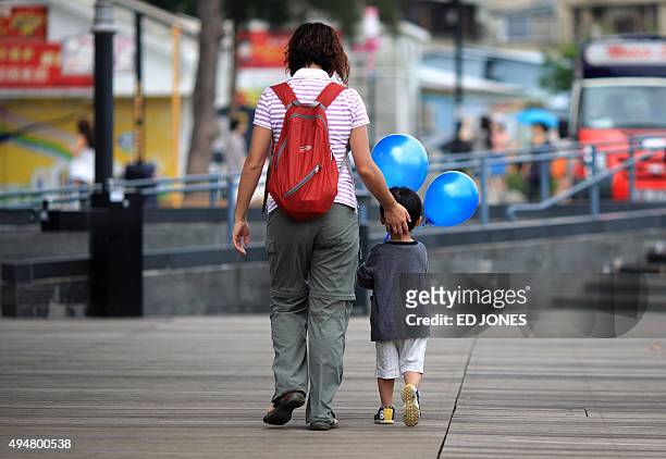 HongKong-lifestyle-education-parenting,FEATURE' by Judith Evans A woman walks with a child holding balloons in Hong Kong on June 4, 2011. Since Amy...