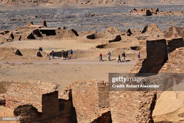 Visitors walk through the ruins of a massive stone complex at Chaco Culture National Historical Park in Northwestern New Mexico. The communal stone...