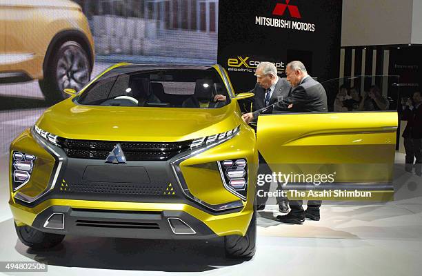 Suzuki Motor Co Chairman Osamu Suzuki inspects an electric vehicle at Mitsubishi Motors booth during the Tokyo Motor Show at Tokyo Big Sight on...