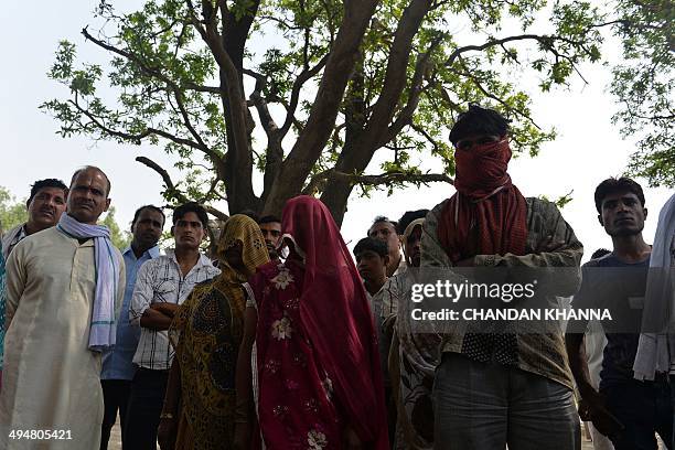 The mothers of gang-rape victims and villagers stand in front of the tree where the bodies of the two girls were found hanging, in Katra Shahadatgunj...